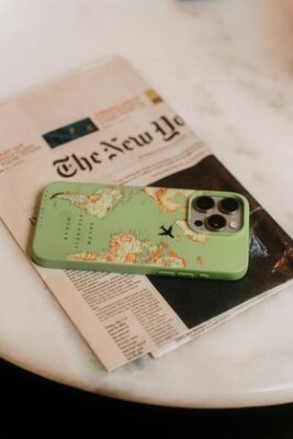 newspaper and cellphone on a table that sources of news around the world