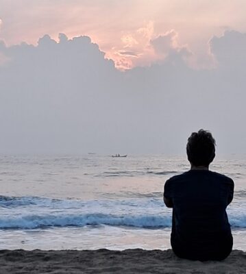 yoga influences all levels of human existence as shown with a women sitting silently observing the ocean
