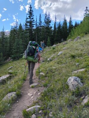 author backpacking a mountain trail created by thousands of others that came before her