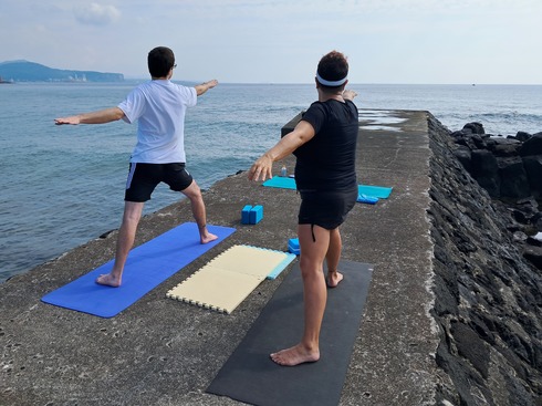 two people in warrior one pose by the ocean